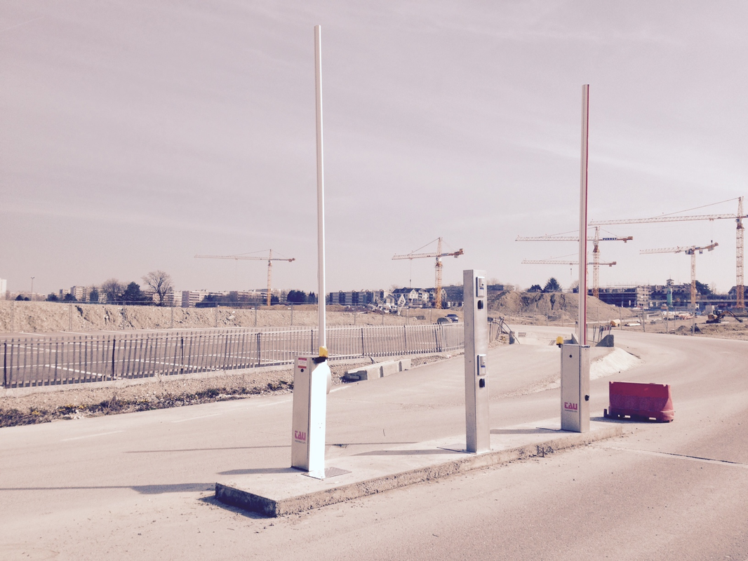 Fourniture et pose de deux barrières automatiques TAU de parking avec potelet Inox pour système d'interphonie et lecteur de badge de contrôle d’accès à l'entré d'un chantier à Meyrin (GE)